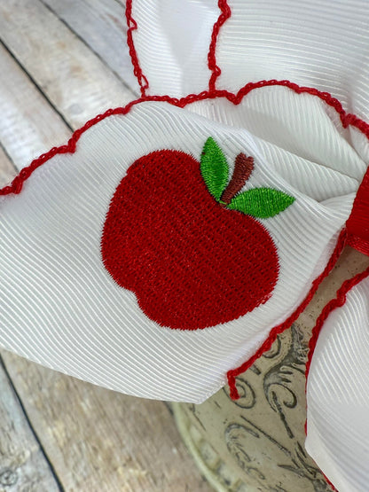 Close up of white apple embroidery on moonstitch bow headband
