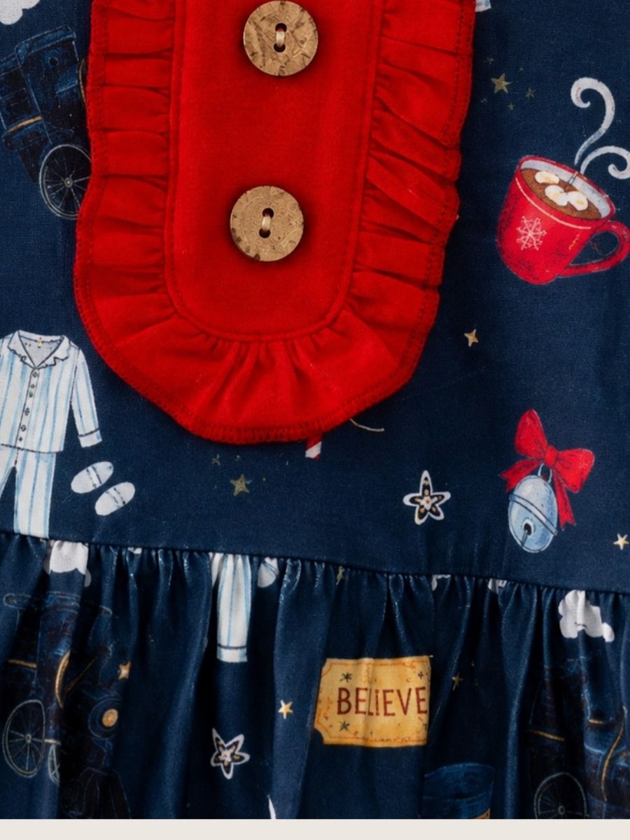 Close-up of girls Christmas train ruffle dress with red ruffle bib, wooden buttons, and vintage holiday train print fabric detail.